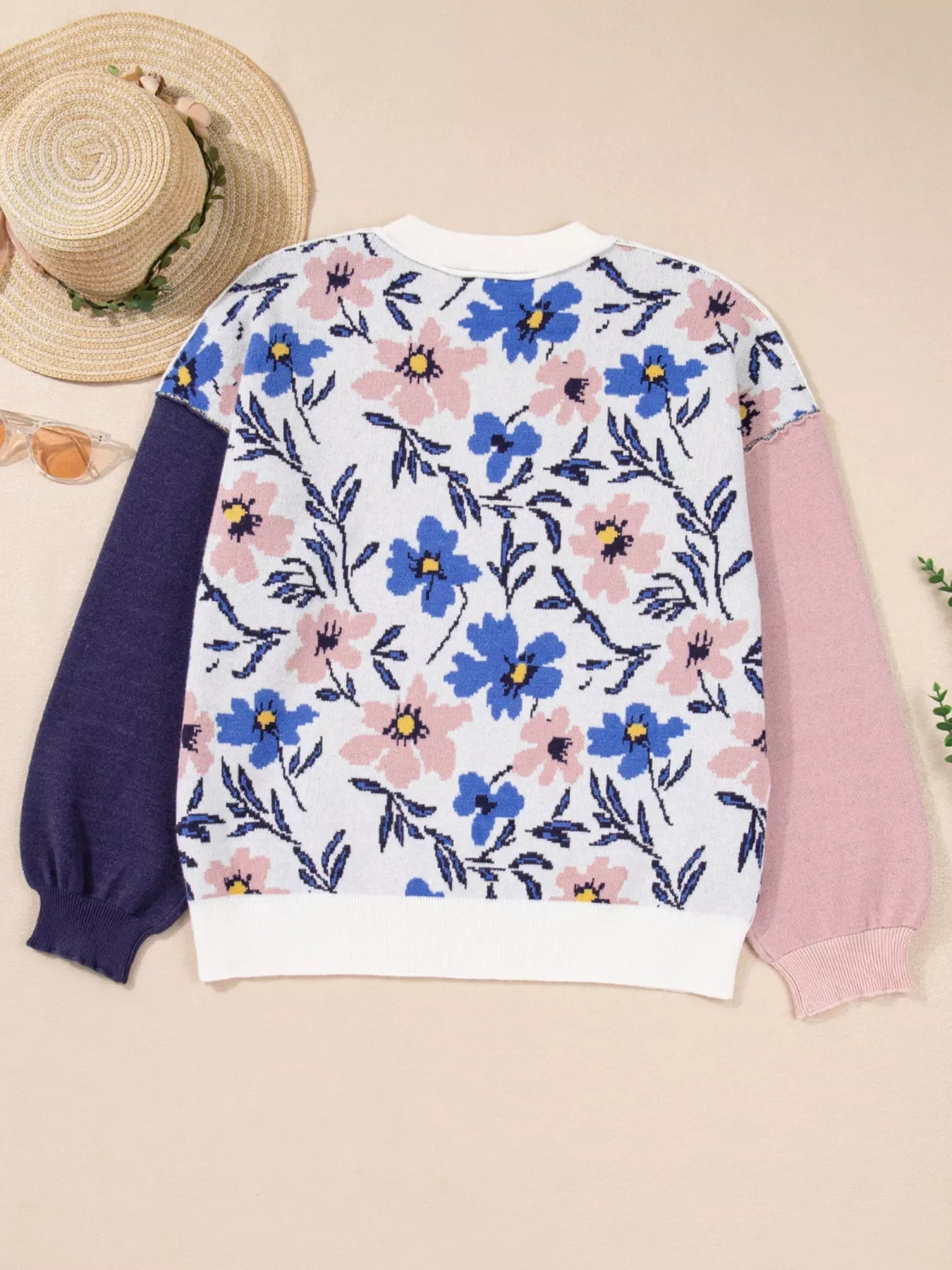 Patchwork sweater with floral design, featuring blue and pink flowers on white, with navy and pink sleeves.