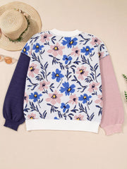 Patchwork sweater with floral design, featuring blue and pink flowers on white, with navy and pink sleeves.