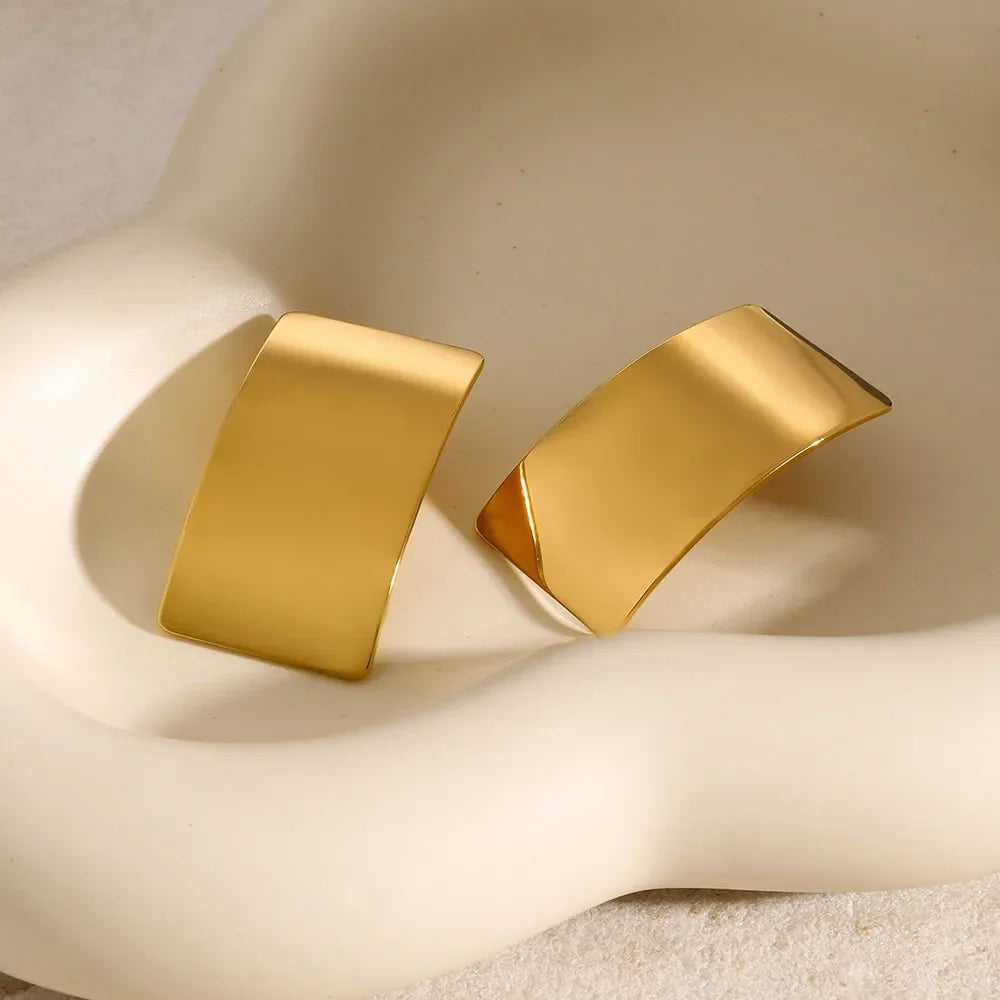 Sculpted gold-tone statement earrings with a bold, curved design.