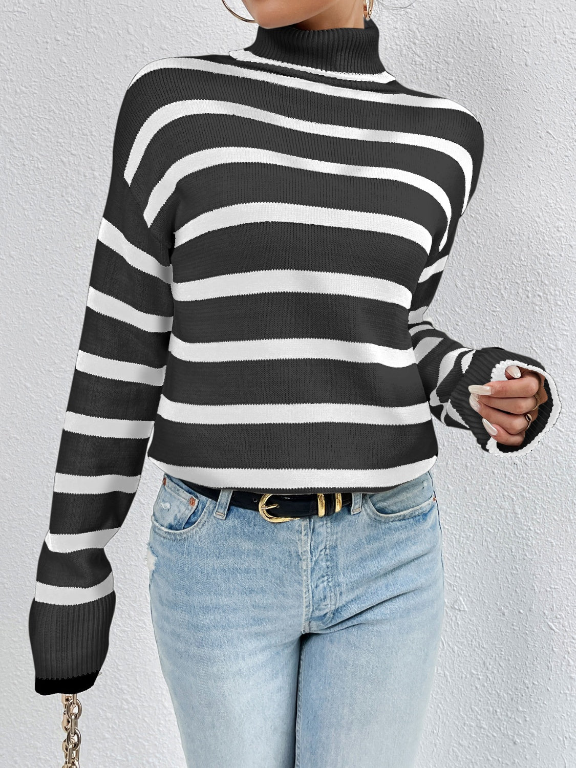 Oversized black and white striped turtleneck sweater with ribbed cuffs.