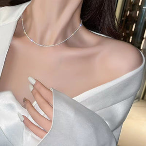 Sterling choker necklace with delicate sparkle, worn on collarbone.
