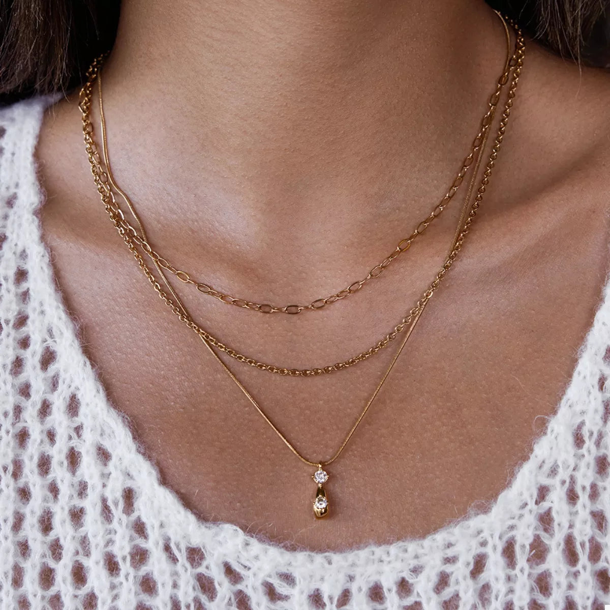 Gold three layered pendant necklace with two small clear stones and one oval gold pendant.