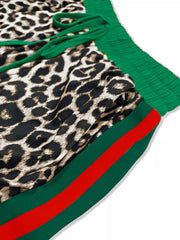 Leopard print lounge pants with green drawstring and green stripe trim with red detail.