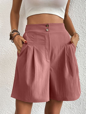 Pleated front bermuda shorts in Dusty Pink with a textured fabric and button closure.