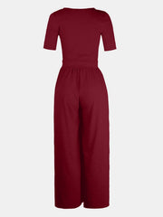 Burgundy textured wide-leg maternity jumpsuit with short sleeves and subtle elastic waist.