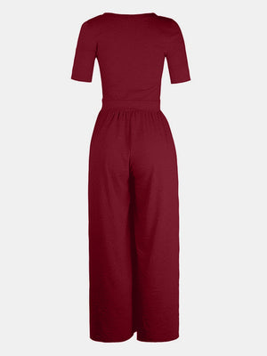 Burgundy textured wide-leg maternity jumpsuit with short sleeves and subtle elastic waist.