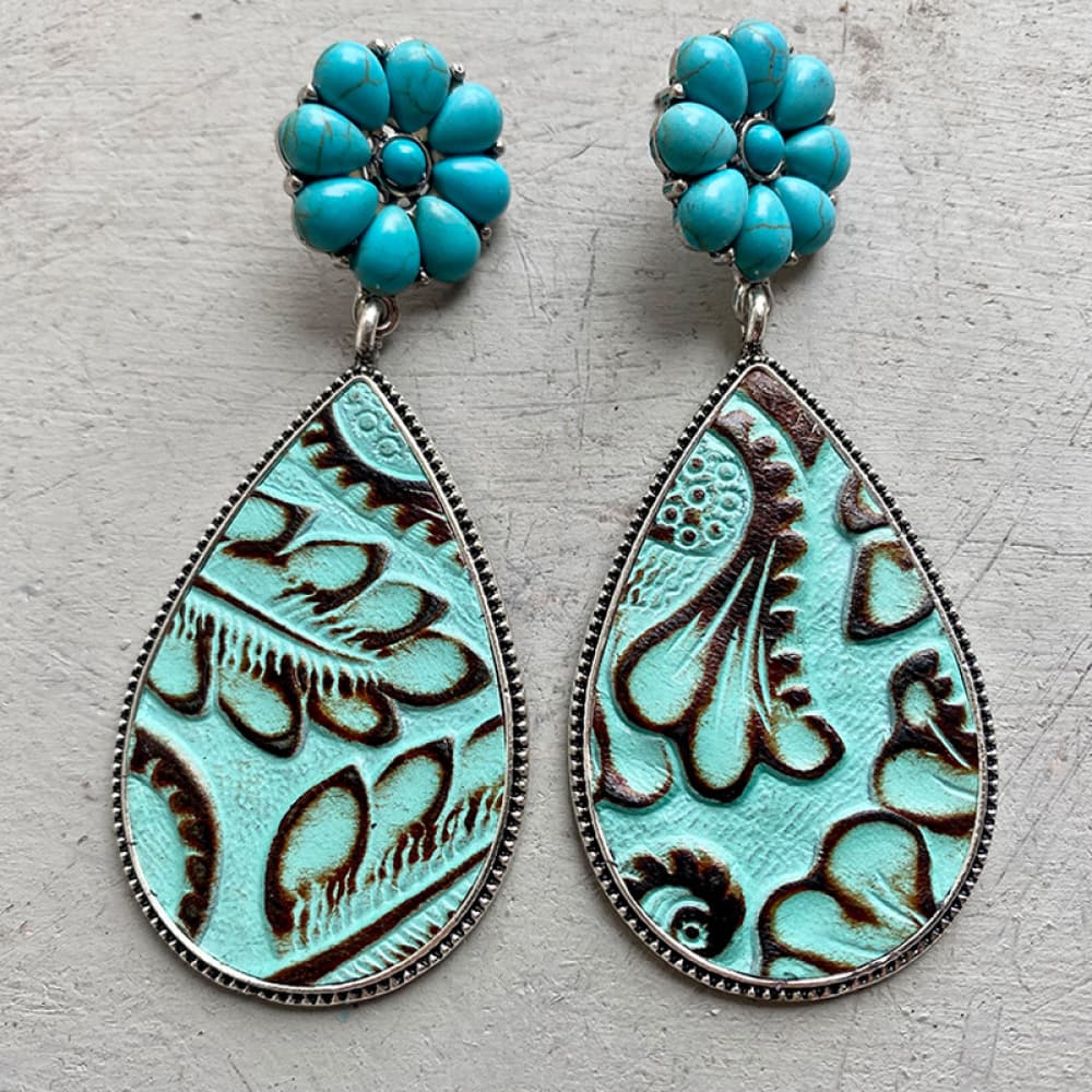 Teardrop earrings with tooled leather, turquoise stones, and silver trim.