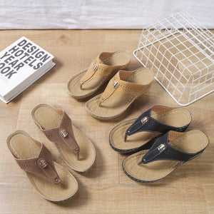 Perforated leather wedge sandals in black and dark brown with thong strap and decorative buckle.