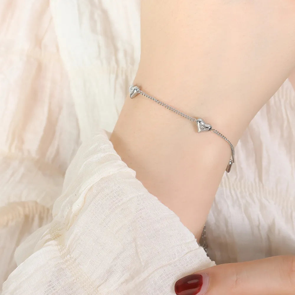 Silver chain bracelet with multiple heart charms and diamond accents.
