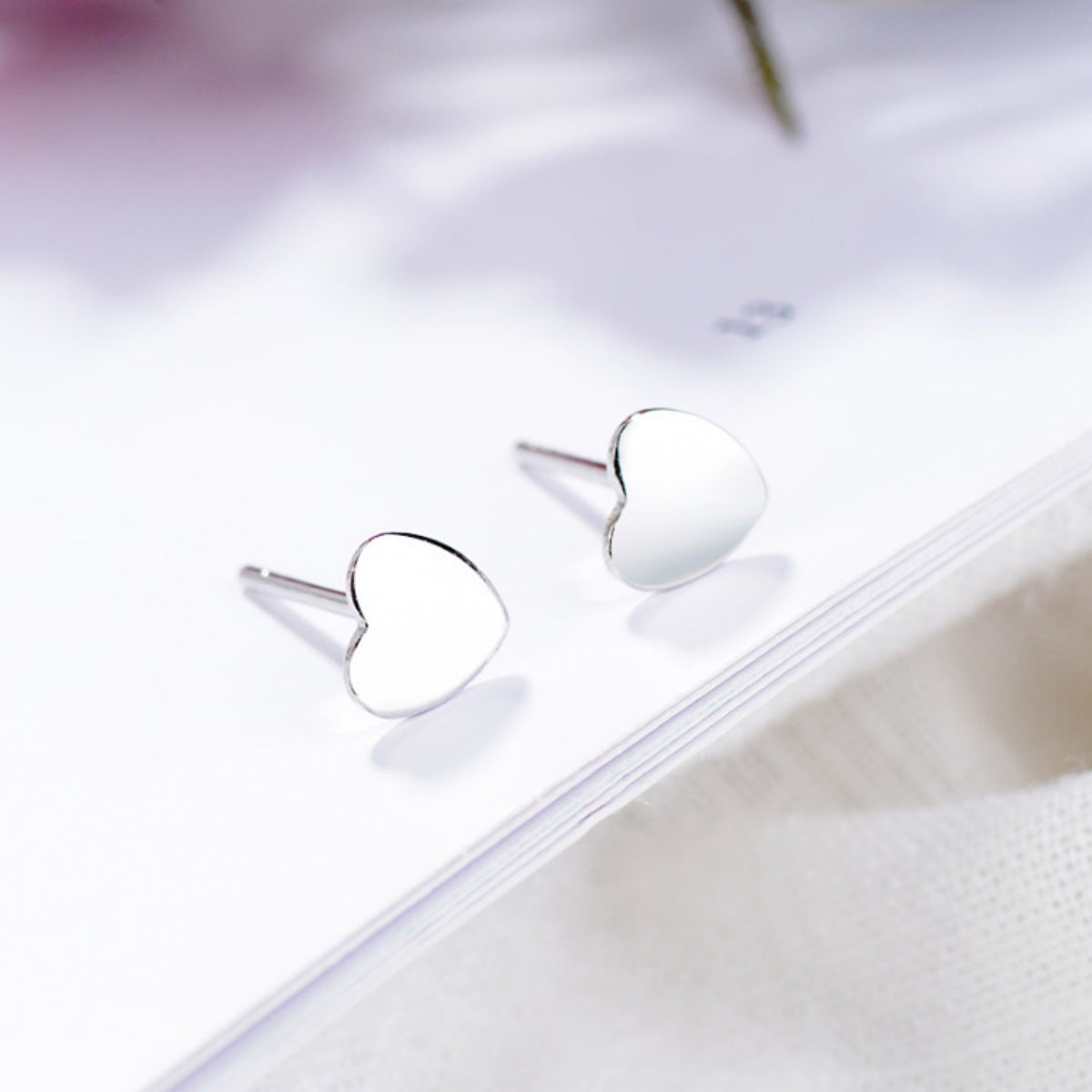 Elegant heart-shaped sterling silver stud earrings with butterfly backs.