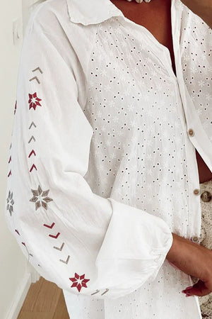 White embroidered eyelet blouse with blouson sleeves featuring geometric and star embroidery.