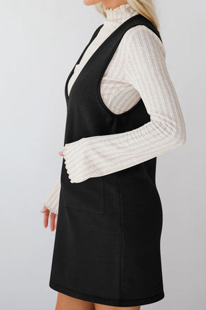 Black V-neck sweater dress with pockets, layered over a cream ribbed mock neck top.