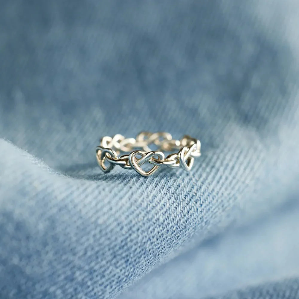 Sterling silver ring with intertwined heart motif, delicate and classic design.