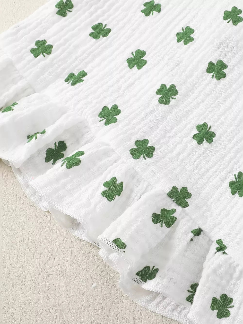 White cotton baby set with green shamrock print and ruffled trim.