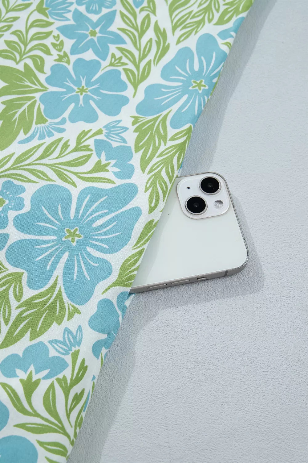 Mini dress with blue floral print and green leaves, showing a phone in the pocket.