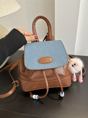 Brown leather mini backpack with denim flap and beaded drawstring detail.