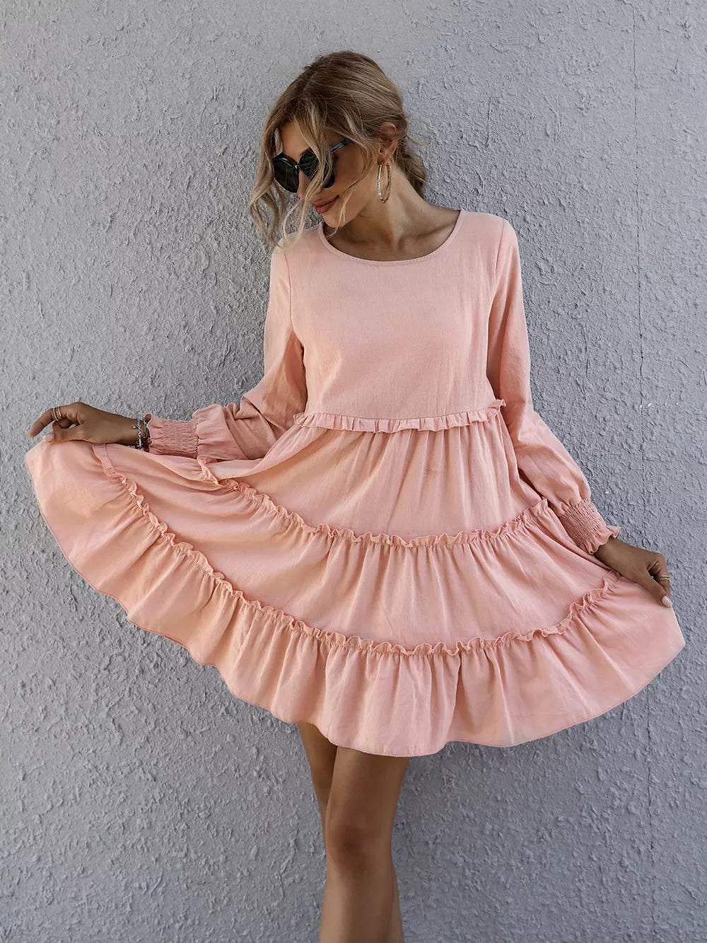 Apricot ruffled mini dress with long sleeves and tiered skirt.