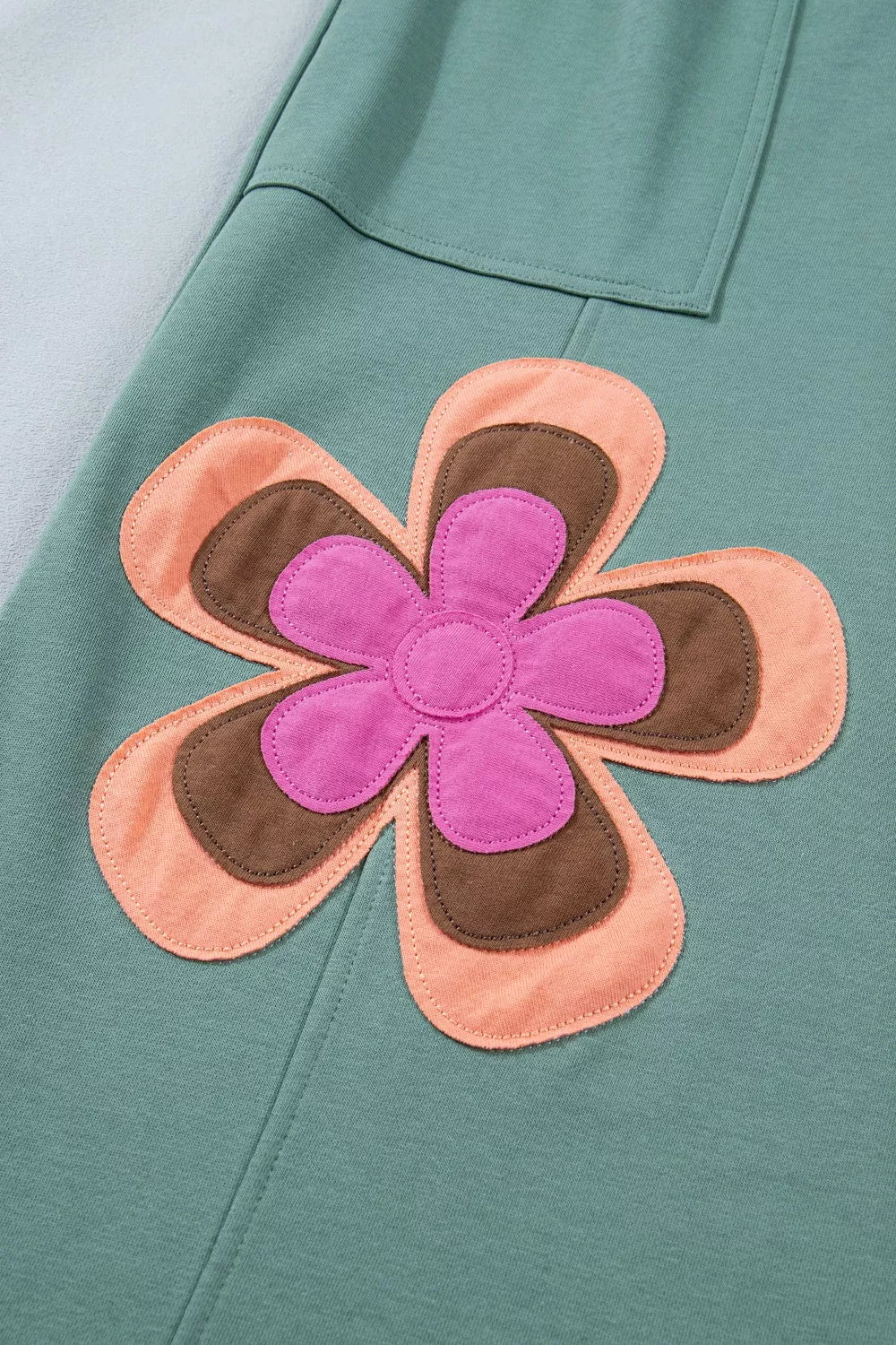 Green cotton sweatpants with a colorful floral applique detail.