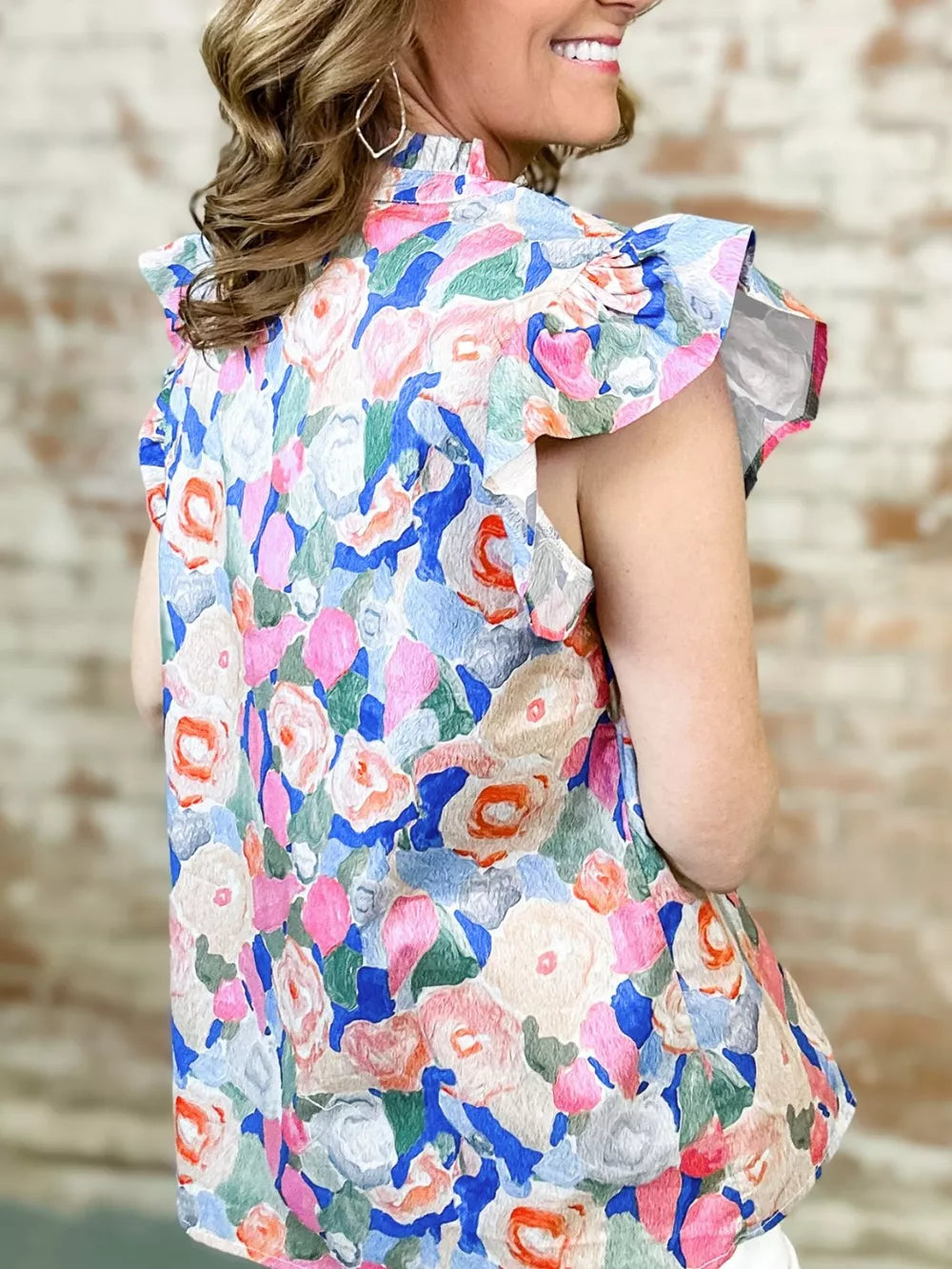 Vibrant floral cotton blouse with tie neck and ruffle sleeves.