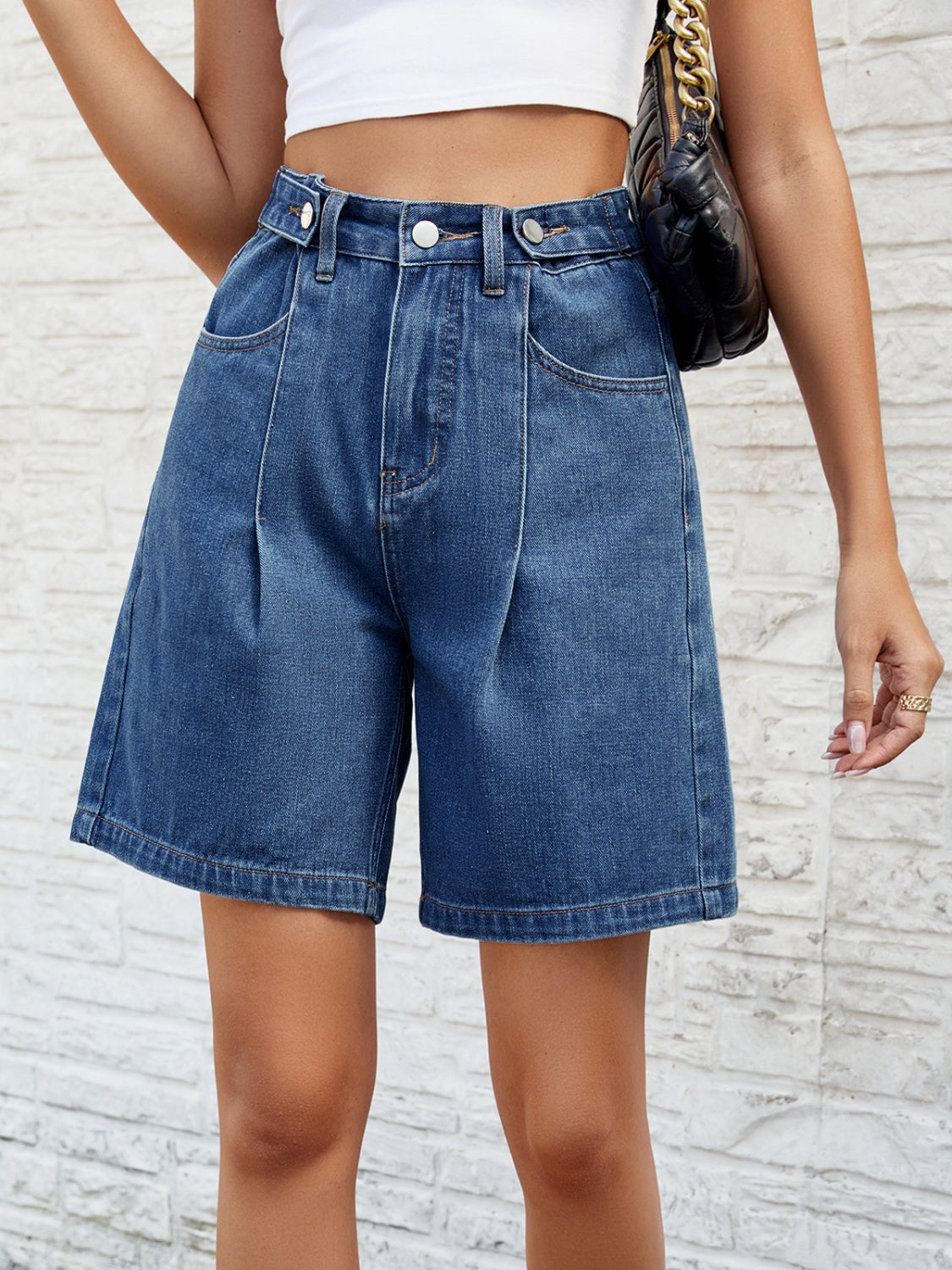 Pleated denim bermuda shorts in medium wash with buttoned fly and wide leg.