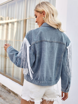 Medium wash denim trucker jacket with white fringe trim on sleeves and shoulders.