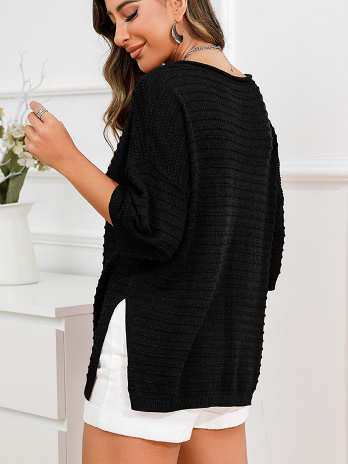 Black textured knit sweater with boat neck and slit hem detail