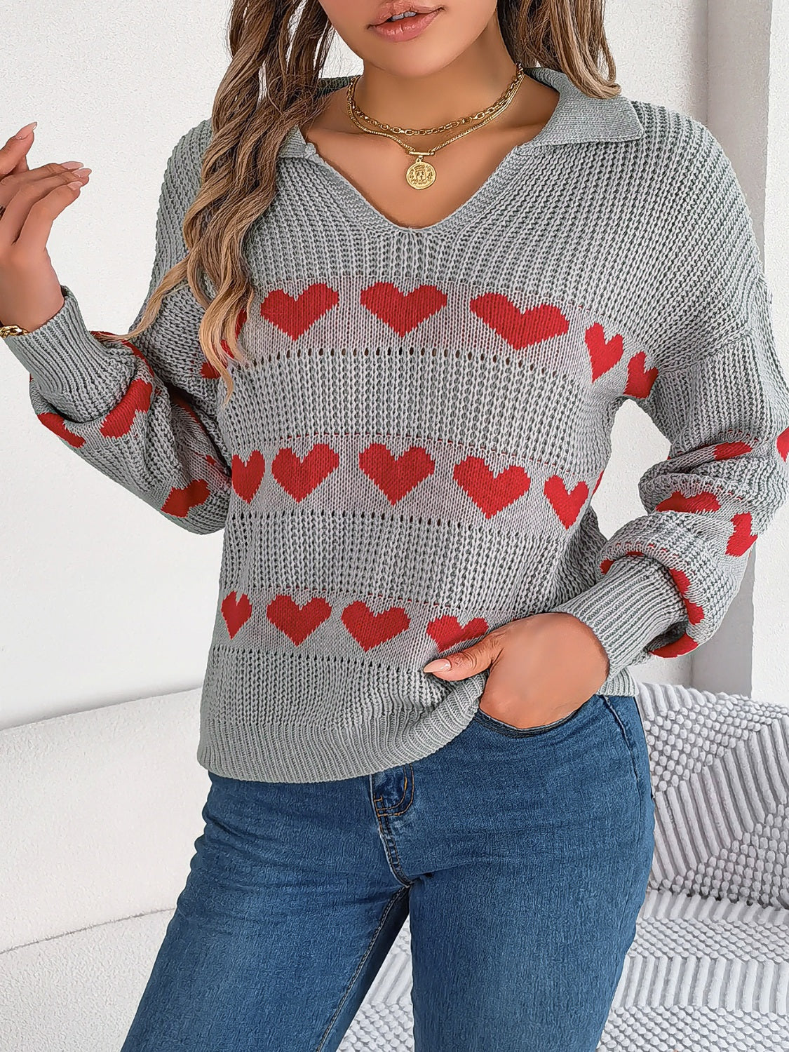 Gray knit polo sweater with red heart pattern and v-neck.