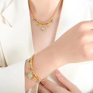 Gold celestial charm bracelet with turquoise accents, featuring tree of life and sunburst charms.