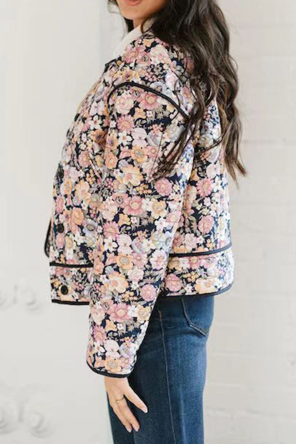 Floral quilted jacket with contrast piping and button detail, worn with jeans.