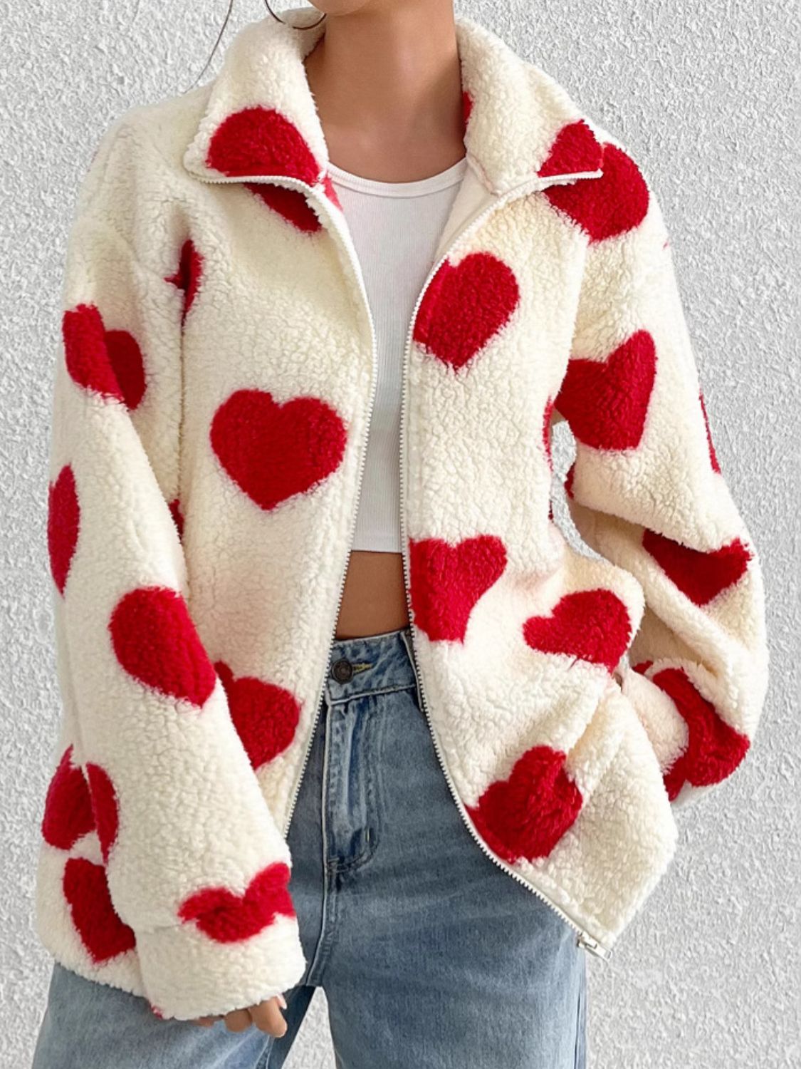 Heart print sherpa zip-up jacket with red hearts on cream fuzzy material.
