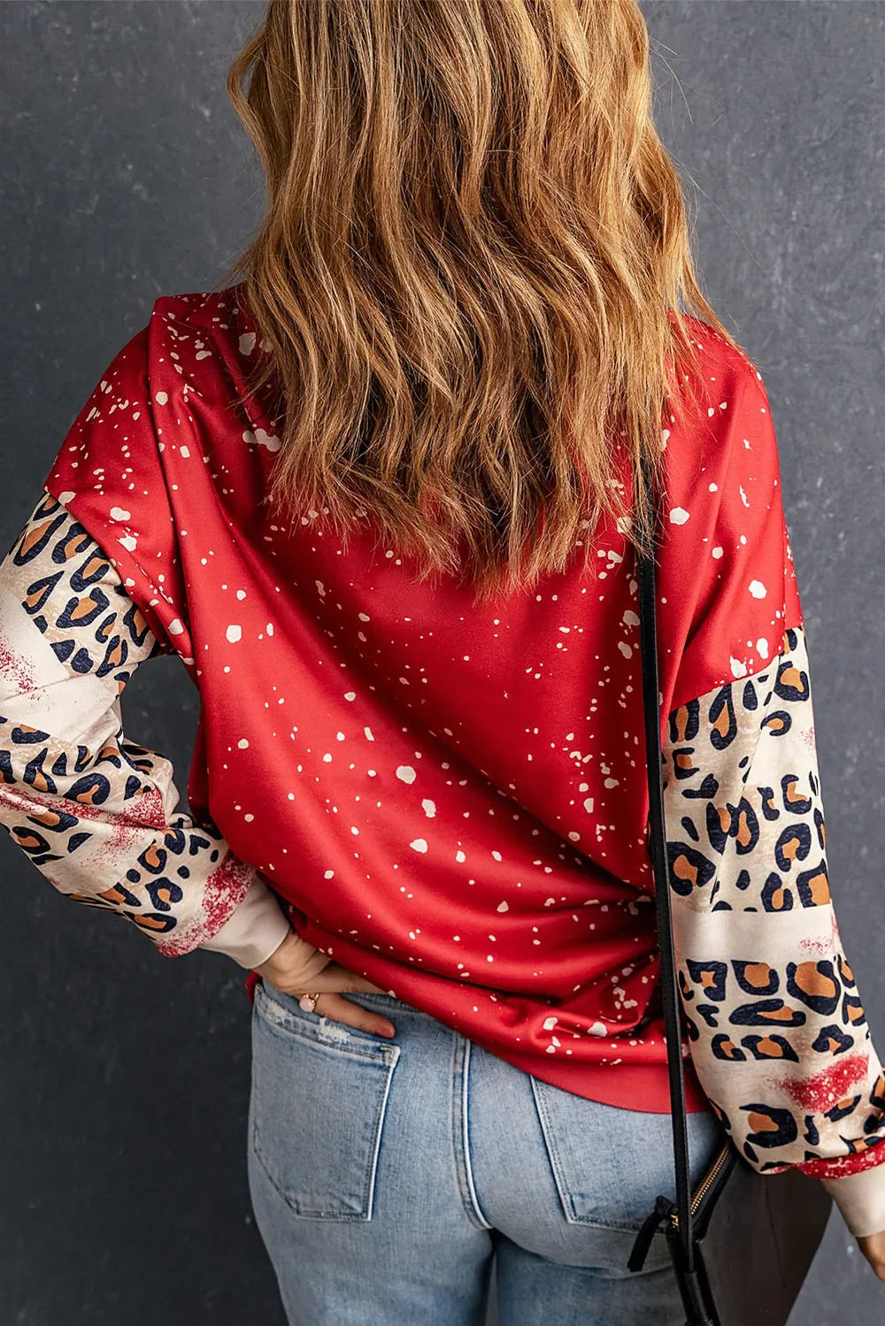 Red sweatshirt with white speckle print and leopard print sleeves.