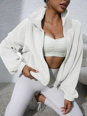 White fleece cropped jacket with funnel neck and zipper closure, styled with a sports bra.
