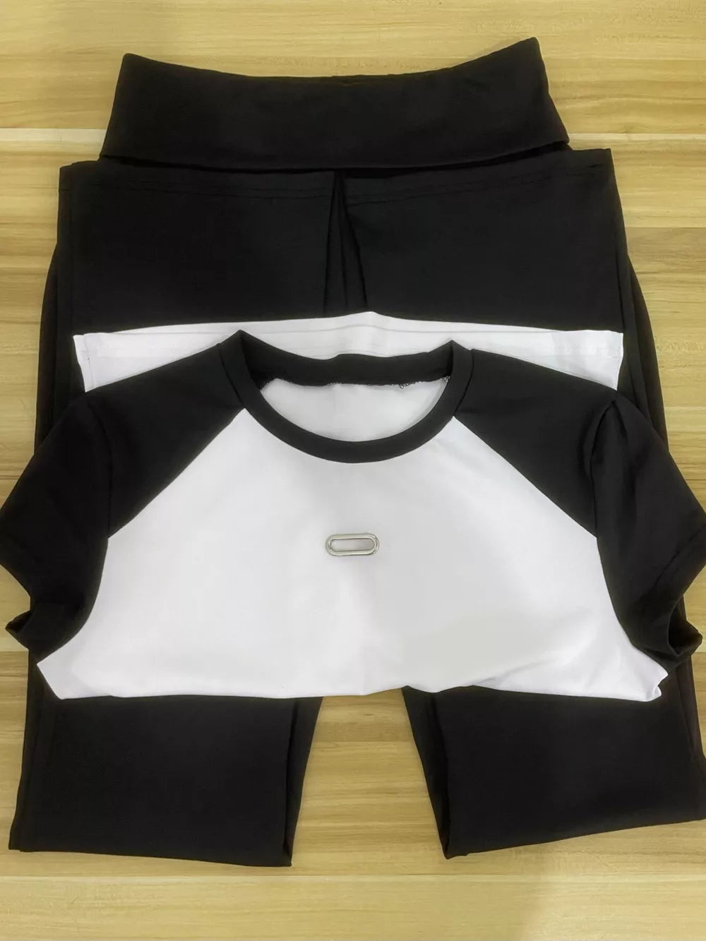 Chic contrast two-piece set with black pants and a white and black raglan sleeve tee with a silver detail.
