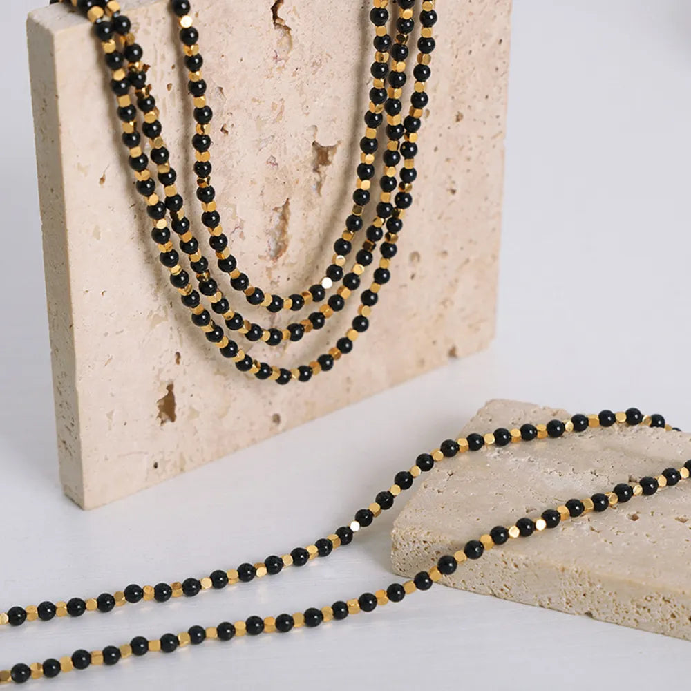Black onyx and gold bead necklace with multiple strands.