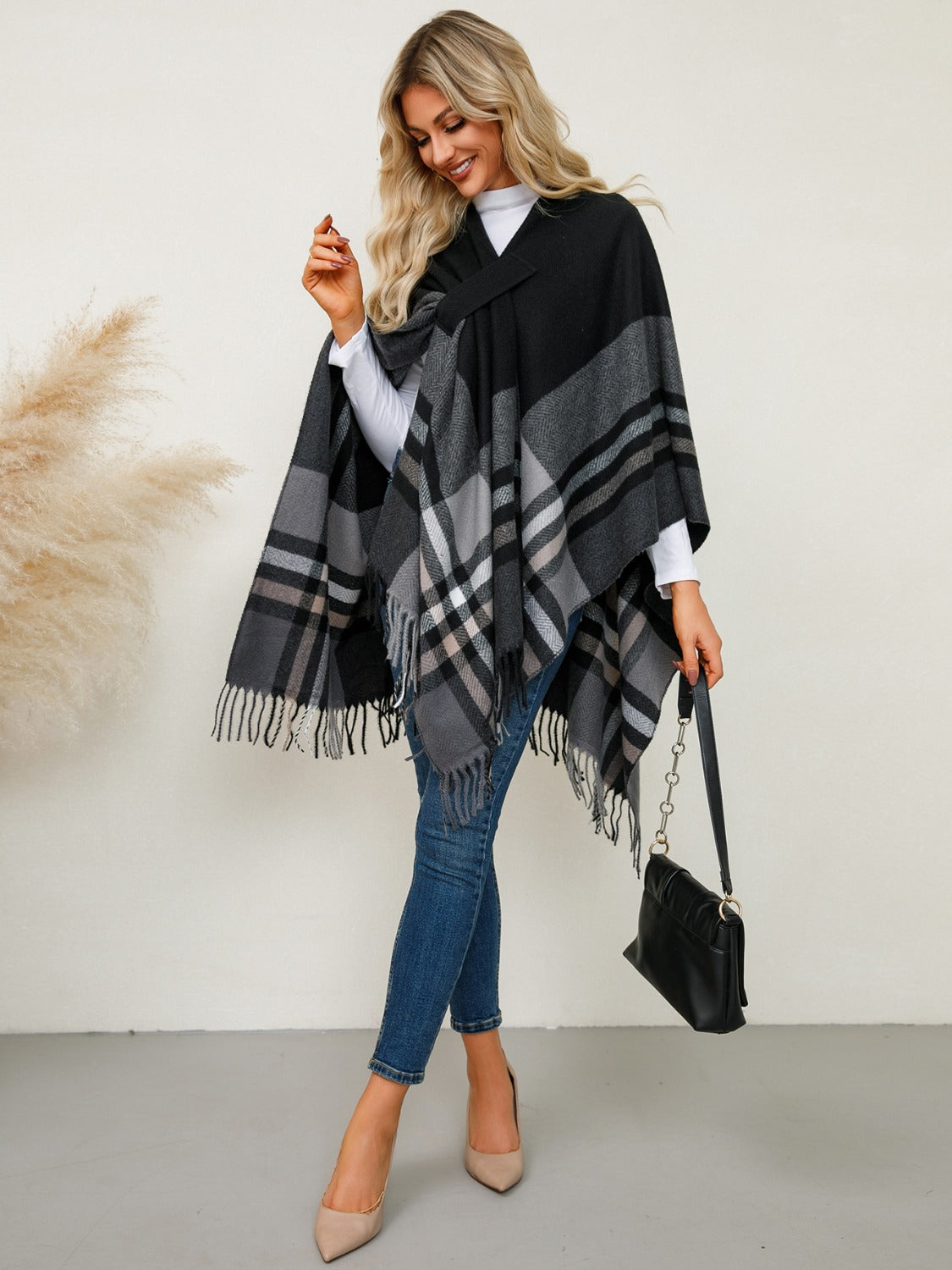 Black asymmetric plaid cape with fringe detail and a cross-over neckline.