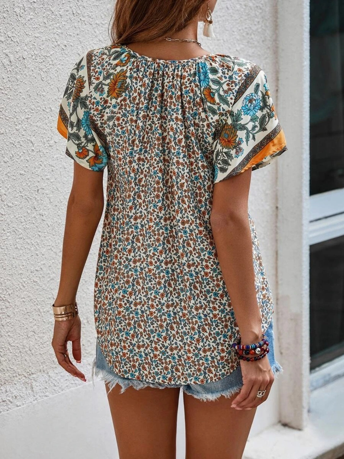 Bohemian floral print blouse with flutter sleeves and a gathered neckline, shown in multicolor.