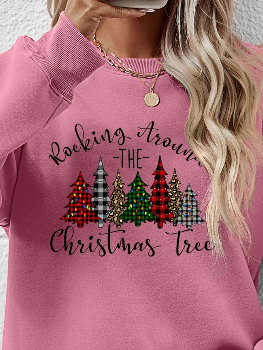 Blush pink crewneck sweatshirt with graphic Christmas trees and text.