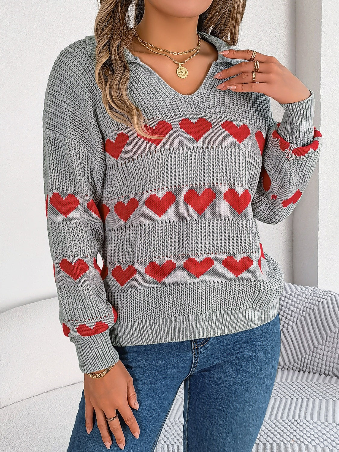 Gray knit polo sweater with red heart stripe pattern and collared neckline.