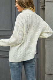 White cable-knit turtleneck sweater with voluminous silhouette and textured acrylic knit.