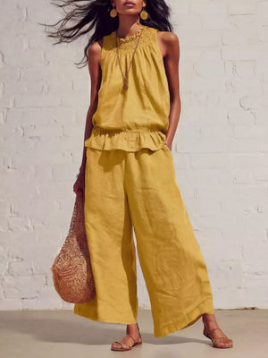 Yellow smocked peplum top and flowing pants set with a ruffled hem and wide legs.