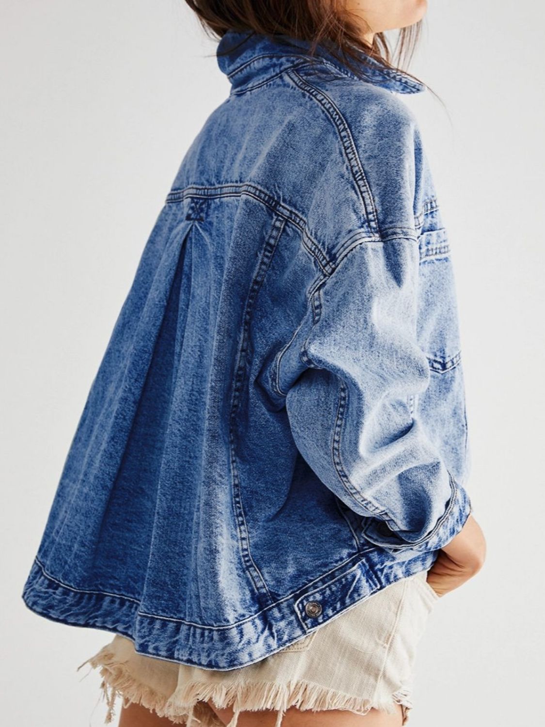 Oversized denim trucker jacket in light blue wash with button closure and pleated back detail.