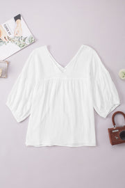 White textured gauze blouse with gathered sleeves and V-neck.