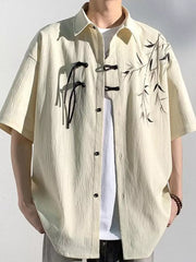 Men's relaxed fit short sleeve shirt in tan with bamboo print and frog button closure.