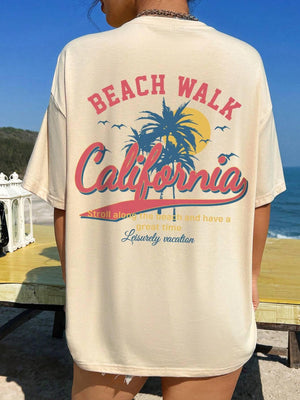 Tan oversized graphic tee with California beach scene and text.