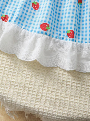 Baby dress with blue gingham and strawberry print, white lace trim.