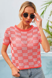 Checkerboard knit crewneck top in orange and white with short sleeves.