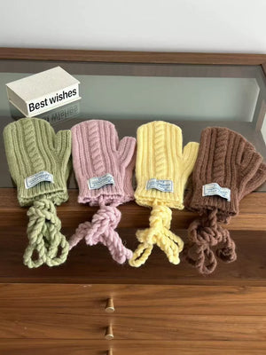 Four cable knit acrylic gloves in green, pink, yellow, and brown with braided ties.