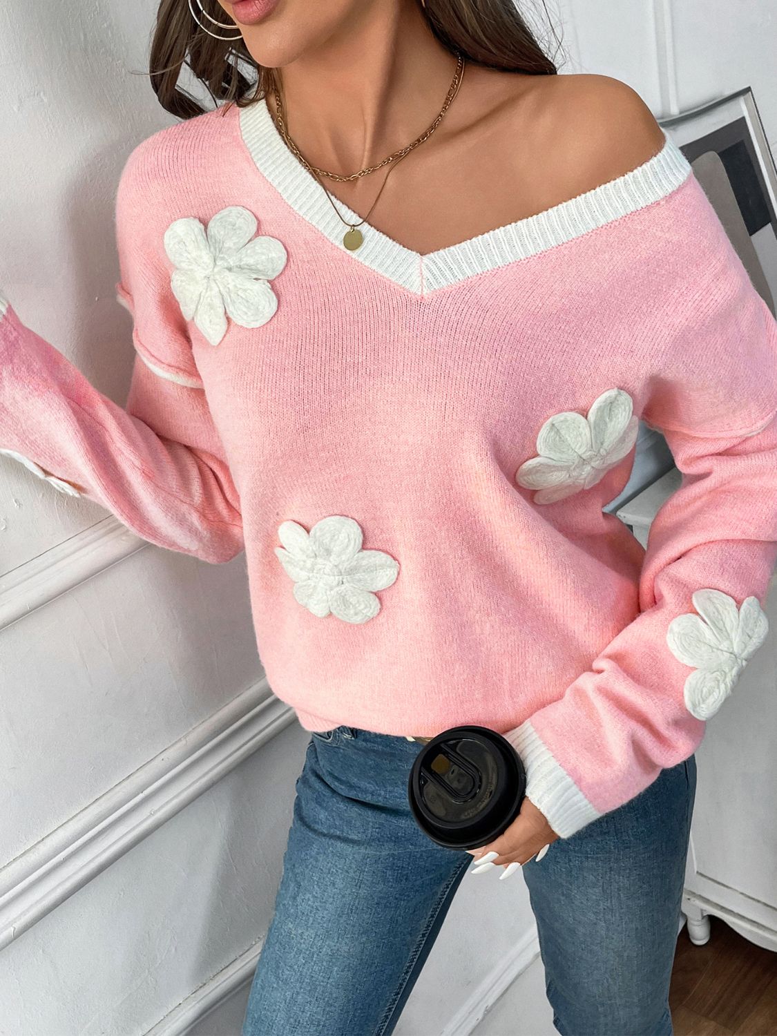 Pink V-neck knit sweater with white embroidered floral appliqués and contrast trim.