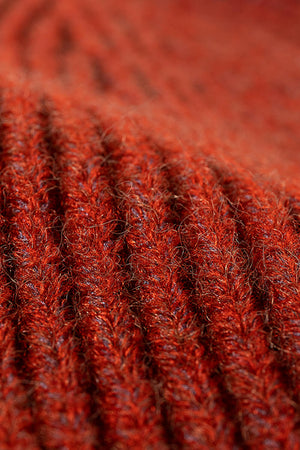 Ribbed acrylic beanie in rust, showing close-up texture.
