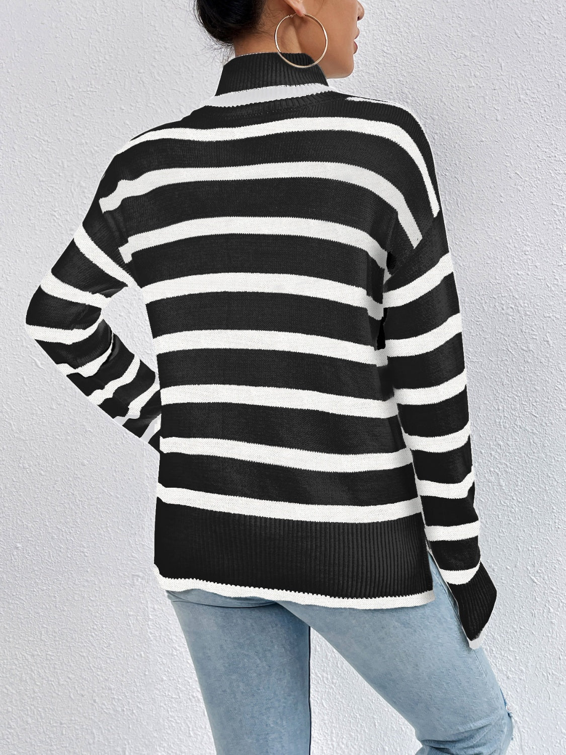 Oversized black and white striped turtleneck sweater with a relaxed fit and side slits.